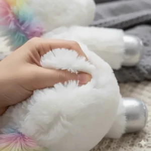 A hand gently squeezing the ultra-soft fabric of the cuddly unicorn plush toy, highlighting its texture.