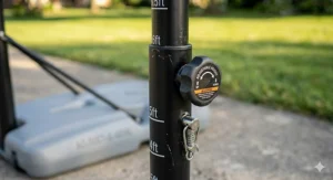 A detailed photorealistic close-up of the telescoping height adjustment mechanism and locking knob on a black kids' basketball hoop pole, showing height markers.