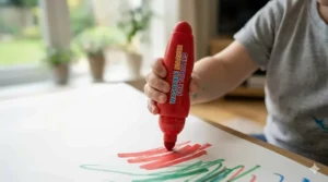 Close-up of a toddler's hand holding a thick, easy-grip marker specifically designed for developing motor skills.