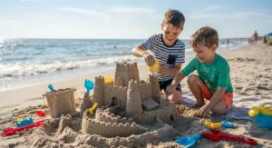 Two brothers building an elaborate sandcastle at the beach using a specialized castle building set of molds and tools.