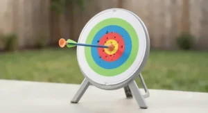 A bright stand-up target board with a foam arrow stuck in the bullseye from a boys archery toy set.